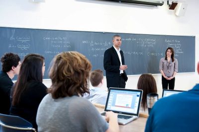 Students seated in a classroom are listening to a lecture