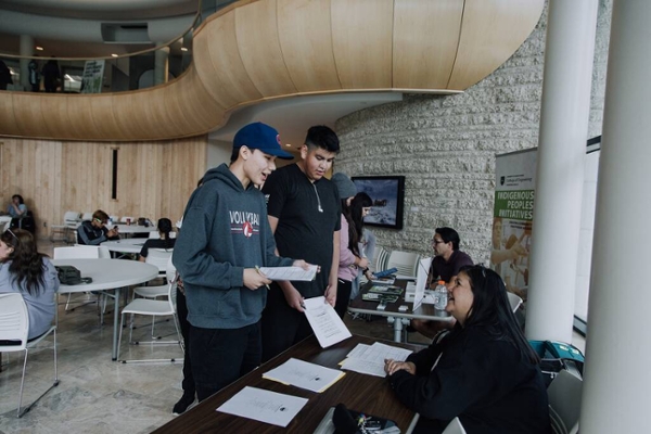 Two students meet a USask staff member at an information fair